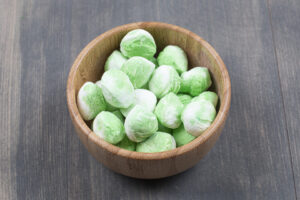 Pile of green candies in wooden bowl